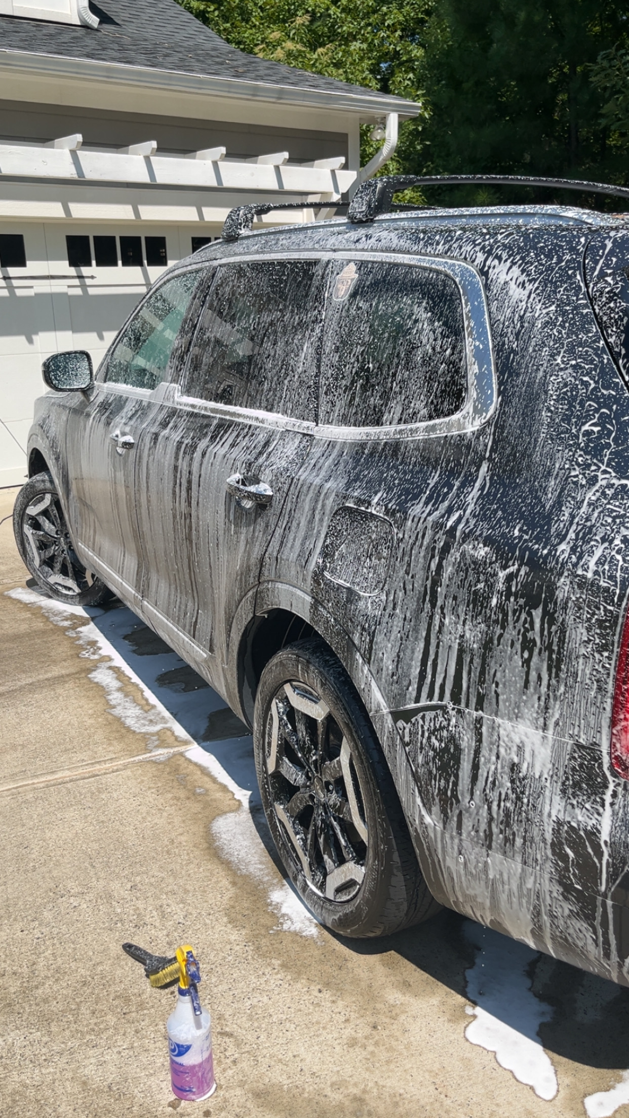 SUV covered in white foam during a mobile hand wash in the driveway